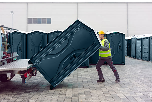 man loading portable restroom at a job site